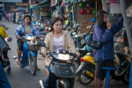 Woman on motorbike in market area